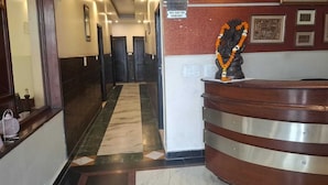 A hotel reception area with a marble floor, a reception desk, and a statue of a deity adorned with a garland. - Hotel Sunder Palace (Dehradun)