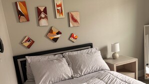 A bed with a quilt, a bedside table with a lamp, and abstract art on the wall. - Charming 3-bedroom 2 bath house in lively Houston (Houston)