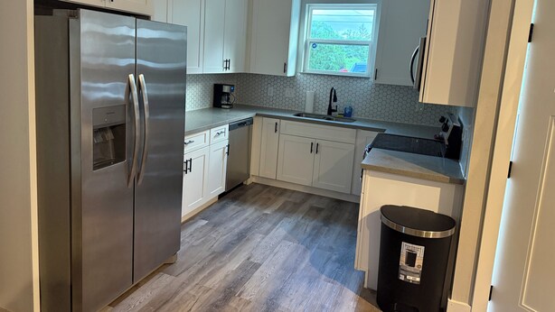 A modern kitchen with white cabinets, a stainless steel refrigerator, a coffee maker, and a window. - Charming 3-bedroom 2 bath house in lively Houston (Houston)