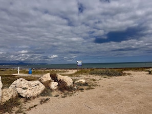 Eine Küstenlandschaft mit einem Wegweiser, felsigem Gelände und einem Blick auf das Meer in der Ferne.