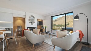 Un salon moderne comprenant un coin repas, une cheminée et une grande fenêtre donnant sur une vue imprenable sur les montagnes.