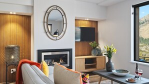 Un salon moderne avec une cheminée, un téléviseur et une vue sur un paysage montagneux.