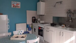 Kompakti keittiö, jossa on pyykinpesukone, kahvinkeitin ja pesuallas.