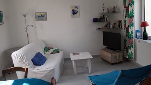 Olohuoneessa on sohva, televisio, pieni pöytä ja tuoli.
