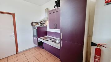 A compact kitchen with a built-in oven, a sink, and a purple cabinet.