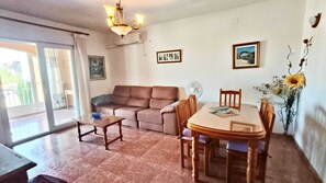 Ein Wohnzimmer mit einer Couch, einem Esstisch mit Stühlen, einer Chandelüster und einem Ventilator.