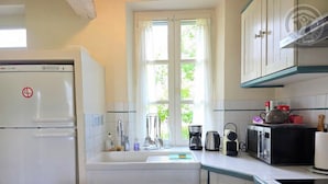 A compact kitchen with a refrigerator, sink, and various appliances including a coffee maker and microwave.