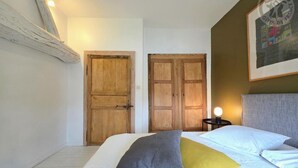 A bedroom with a bed, pillows, a nightstand, and two wooden doors.