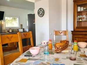 Ein Essbereich mit einem Tisch für zwei Personen, einer Uhr an der Wand und einer Küche im Hintergrund.