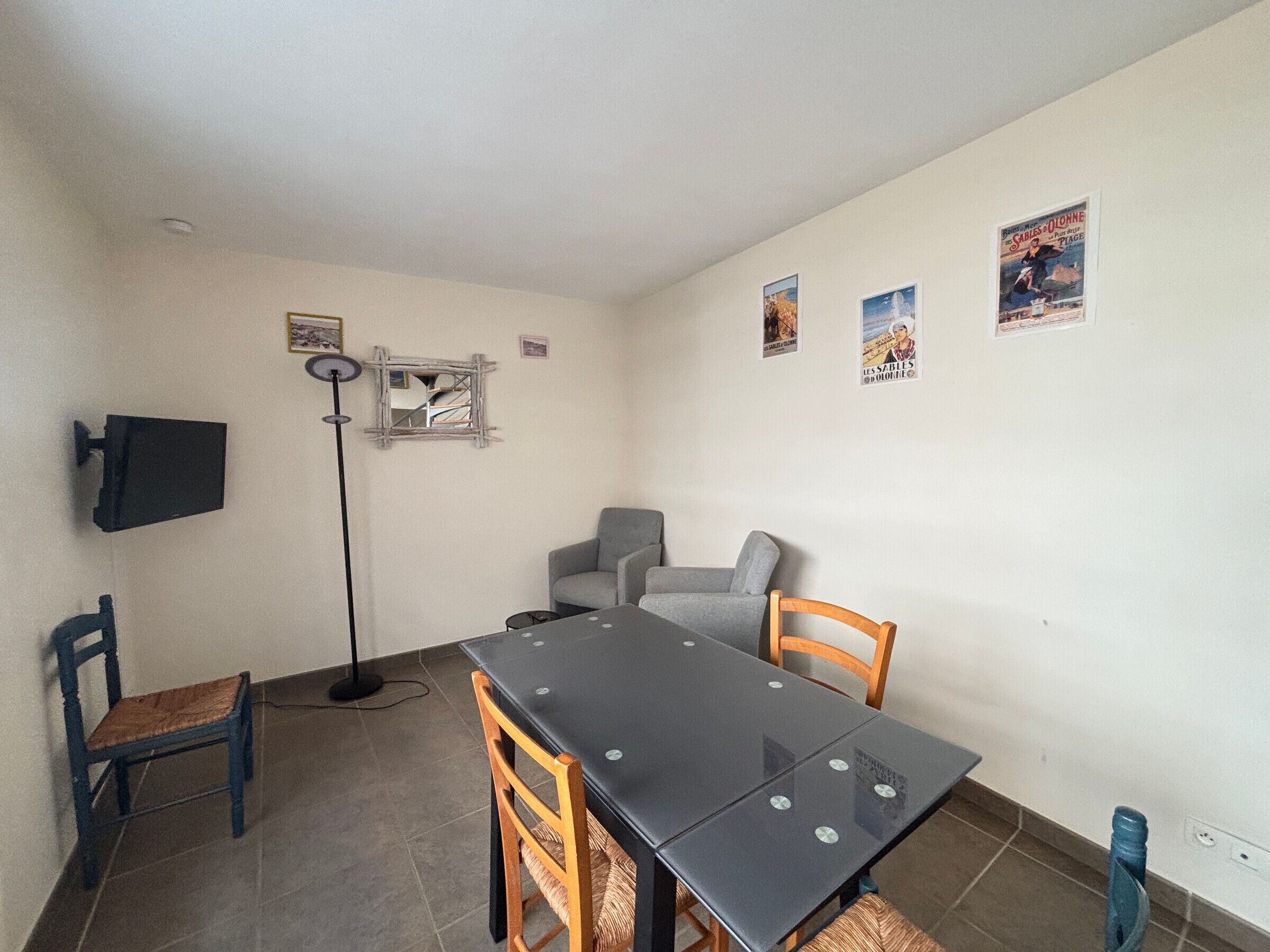 A dining area with a table, chairs, a floor lamp, and wall decorations.