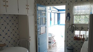 Eine Küche mit blauer Tür, weißen Schränken, einem Esstisch und einem Fenster mit Blick.