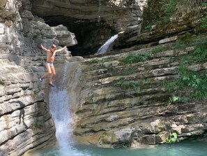 Une personne qui saute d’une falaise rocheuse dans une cascade.