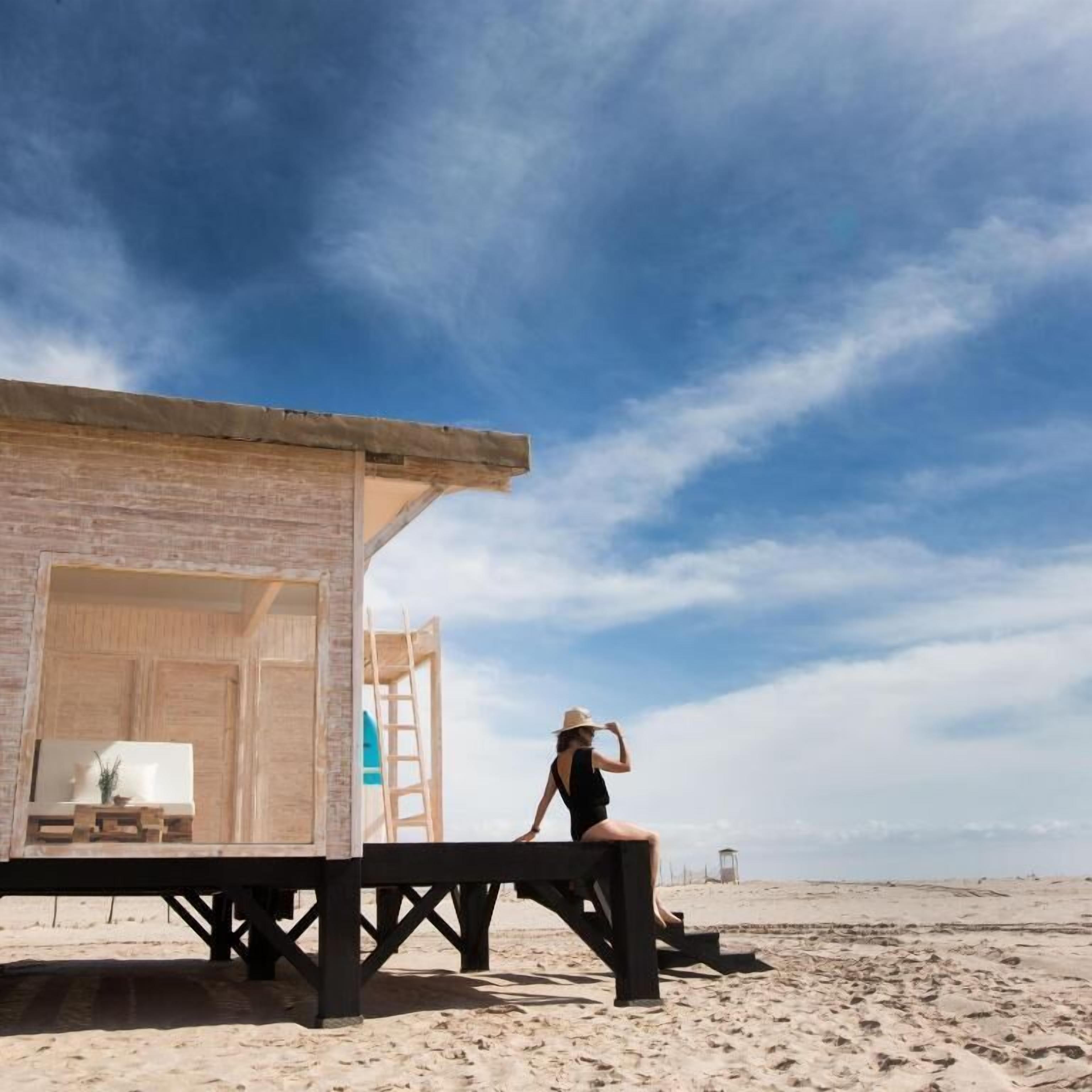 Una struttura fronte spiaggia con un pontile di legno, una scala e vista libera sulla spiaggia.