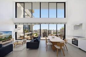 Eine moderne Wohnung mit einem großen Essbereich, einer Couch, einem Fernseher und einer Küche.