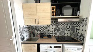 Una cucina funzionale con mobili in legno, lavatrice e forno a microonde.
