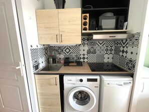 Eine kleine Küche mit Holzschränken, einer Waschmaschine und einer Mikrowelle.