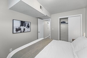 Habitació d'hotel amb un llit, un armari, una porta que dóna a una altra estada i una obra d'art penjada a la paret.