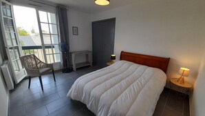 A hotel room with a large bed, a chair, a desk, a wardrobe, and a window with curtains. - Charming T2 city center - 2 guests (La Roche-Posay)