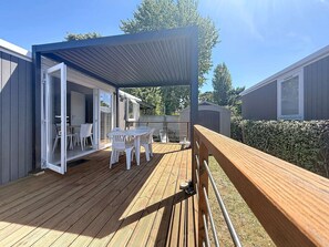 A covered outdoor deck with a table and chairs, a wooden railing, and a view of the surrounding area. - City mobile home, pets allowed - 4 guests (Jullouville)
