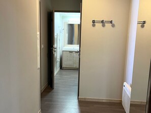 A hallway with a wooden floor, a radiator, and a door leading to a bathroom with a sink and towel rack. - Spacious apartment, pool access - 6 guests (Flaine)