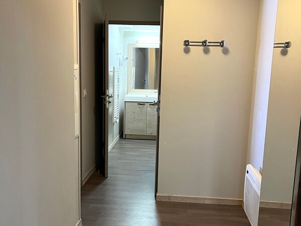 A hallway with a wooden floor, a radiator, and a door leading to a bathroom with a sink and towel rack. - Spacious apartment, pool access - 6 guests (Flaine)