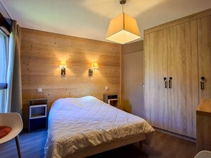 A bedroom with a bed, bedside tables, a wardrobe, and wall-mounted lamps. - Spacious apartment, pool access - 6 guests (Flaine)
