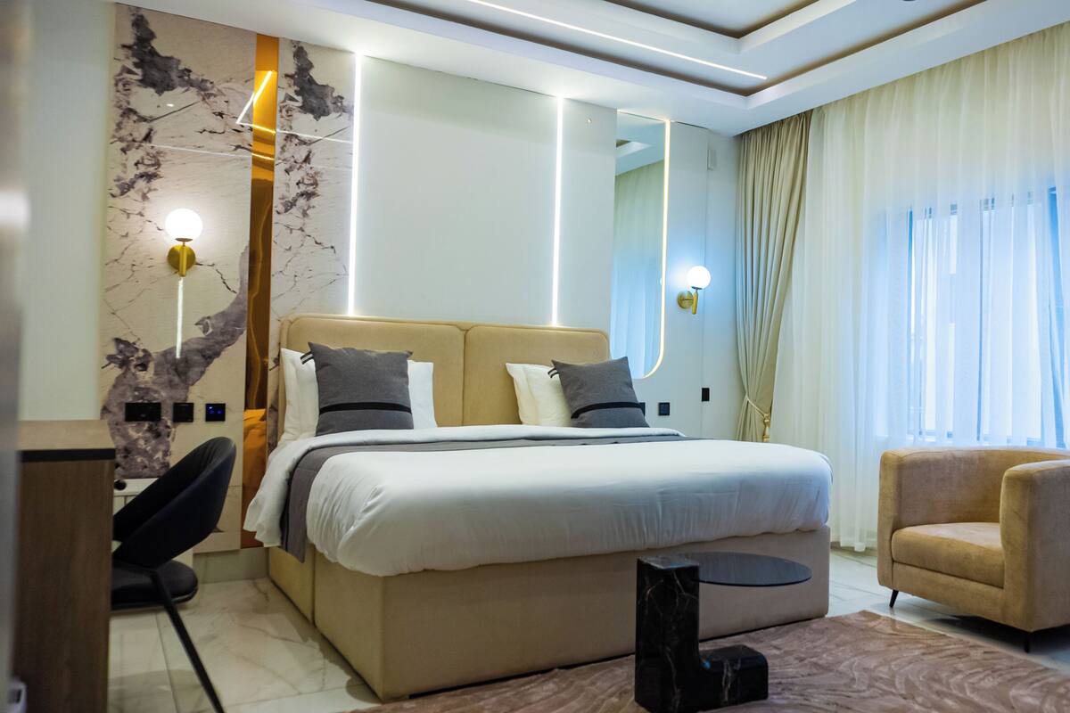 Ein modernes Hotelzimmer mit einem großen Bett, einer Sitzecke und Blick ins Freie.