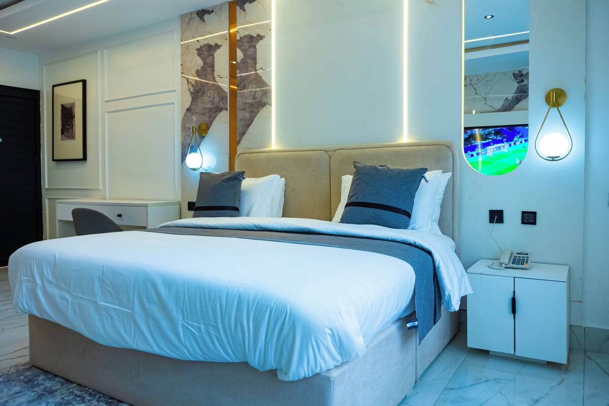 Ein modernes Hotelzimmer mit einem großen Bett, einem Schreibtisch und einem Fernseher.