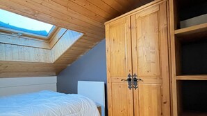 Une chambre avec un puits de lumière, une armoire en bois et un lit.