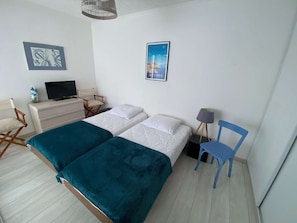 A hotel room with two beds, a desk with a television, a chair, and a poster on the wall. - Duplex sea view, parking - 6 guests (Le Barcarès)