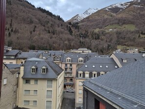 Un quartier résidentiel composé d’immeubles à plusieurs étages, d’une rue et dominé par un paysage montagneux.