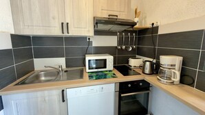 Eine kompakte Küche mit Geschirrspüler, Mikrowelle, Toaster, Kaffeemaschine und Backofen.