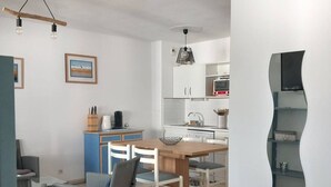 Uma cozinha moderna com armários brancos, uma mesa de jantar com cadeiras e uma estante curva original.