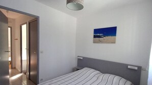 Quarto com cama, quadro, porta e luminária.