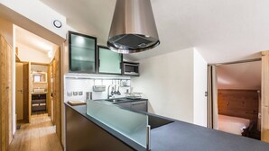A compact kitchen with a central island, stainless steel appliances, and a modern design. - Renovated apartment, ski-in/ski-out - 5 guests (Val-d'Isère)