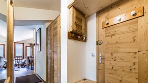 A wooden hallway with a bench, a door with a coat of arms, and a view of a balcony with outdoor furniture. - Renovated apartment, ski-in/ski-out - 5 guests (Val-d'Isère)