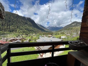 A balcony with a view of a valley, mountains, and a village. - Comfortable duplex apartment - 7 guests (Châtel)
