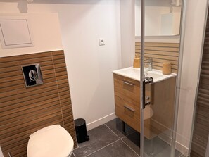 Ein modernes Badezimmer mit Toilette, Waschbecken und Spiegel.