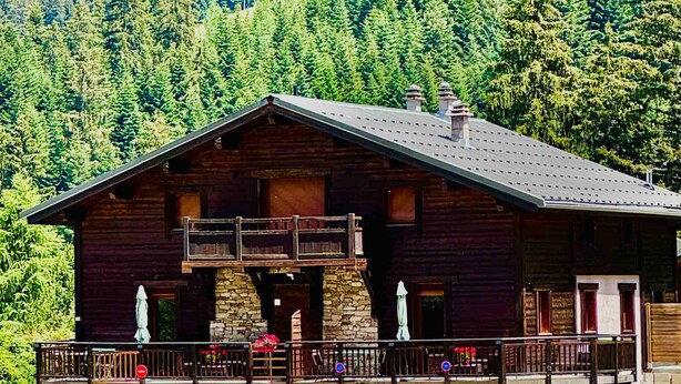A log cabin with a balcony, stone foundation, and a stone wall in front. - New cozy apartment with balcony and private parking in Pralognan-la-Vanoise (Pralognan-la-Vanoise)