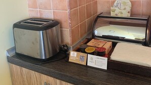 Ett köksutrymme med en brödrost, en brödlåda och ett vitrinskåp med livsmedel.
