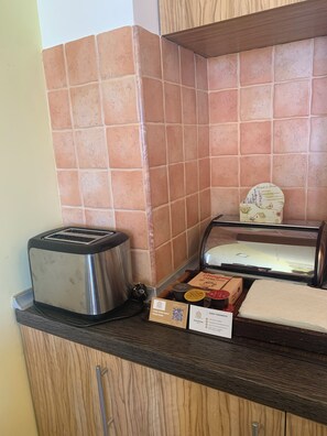 Una zona de cocina con un tostador, un panera y una vitrina con alimentos.