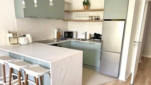Eine moderne Küche mit Kochinsel, Barhocker, Mikrowelle und Kühlschrank.