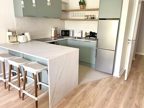 A modern kitchen with a central island, bar stools, a microwave, and a refrigerator. - Luxury By The Coast 7 (Galway)