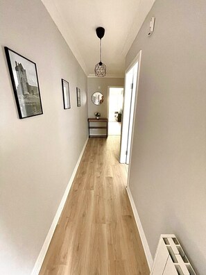 A hallway with wooden flooring, a ceiling fan, and framed pictures on the walls. - Luxury By The Coast 7 (Galway)