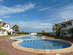 A swimming pool with two separate sections, surrounded by palm trees and a clear sky. - Apartment in Denia - Perfect for Your Vacation (Denia)