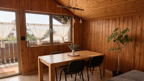 Ein Zimmer mit Holzwandverkleidung, einem Holztisch, vier Stühlen, einem Blumentopf und einem Bett.