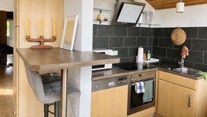 Eine moderne Küche mit Holzausziehtisch, eingebautem Backofen und schwarzem Fliesenrückwand.