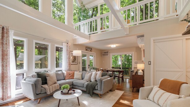 A spacious living room with a large sectional sofa, a round coffee table, and a dining area with a table and chairs.