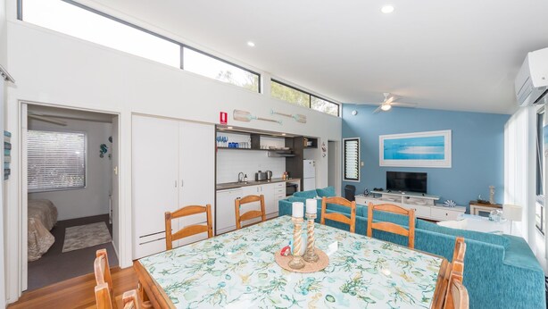 A compact living space with a dining area, kitchenette, and a large window. - Sandy Shores, Serenity Resort (Diamond Beach)