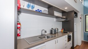 A modern kitchen with white cabinets, a stainless steel sink, and a built-in oven. - Sandy Shores, Serenity Resort (Diamond Beach)